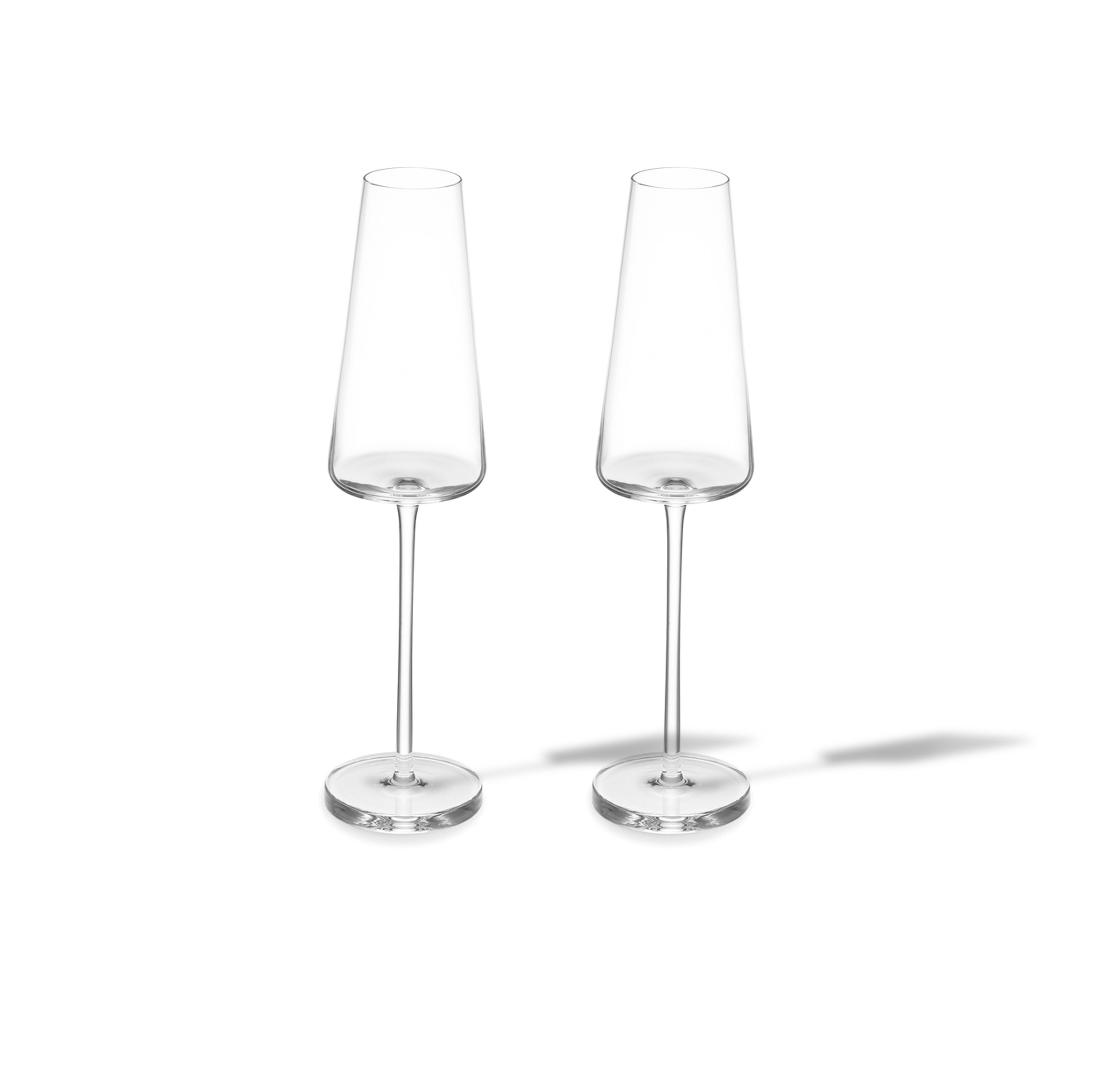 Deux flûtes à champagne Lasvit Sommelier, transparentes et vides, avec de hautes tiges et de larges bases, se trouvent côte à côte sur un fond blanc, projetant des ombres subtiles - un ajout raffiné à toute collection.