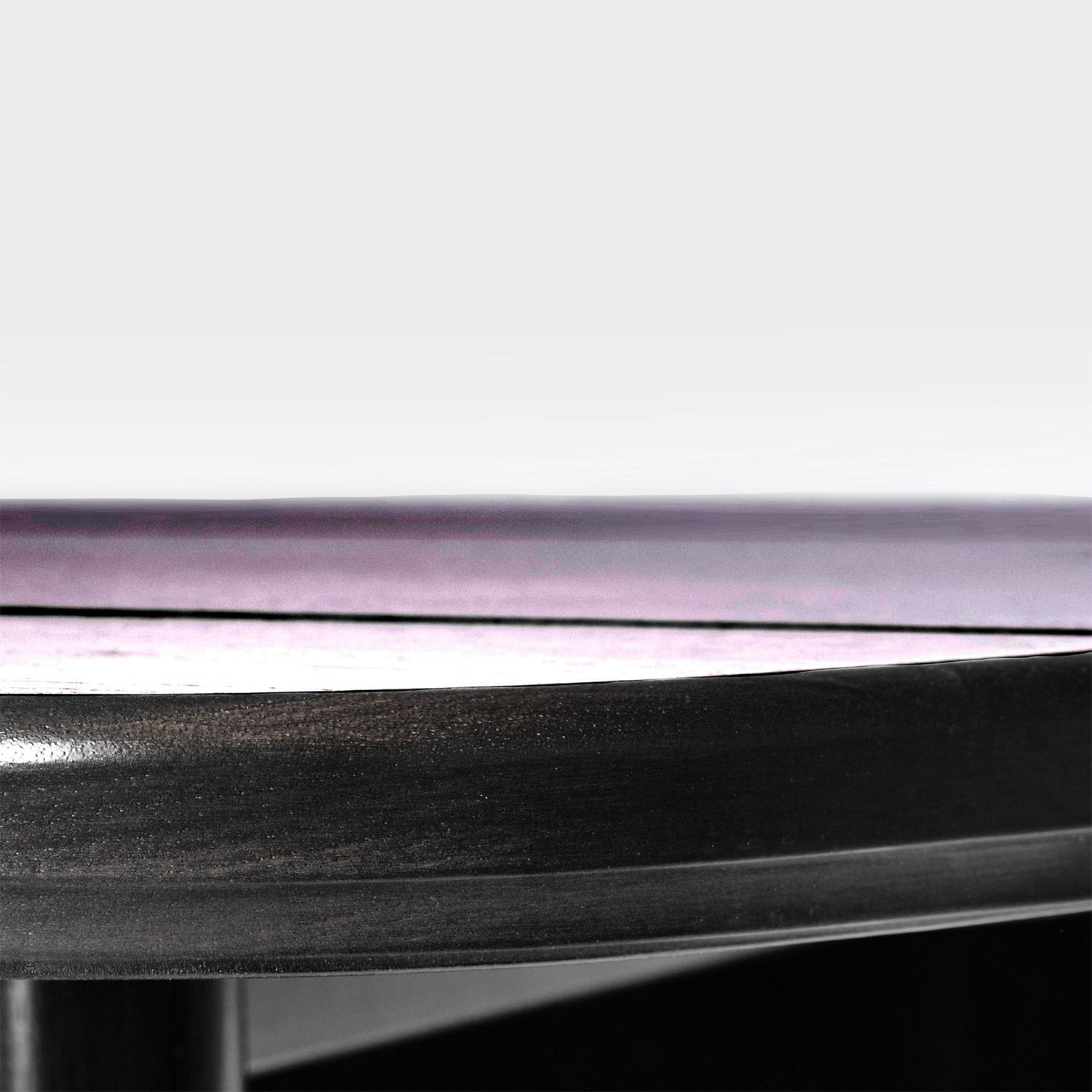 Gros plan de la surface en bois foncé de la table extérieure Horizon 132" │ Noir de Humble Nature. Elle met en valeur la texture et le bord arrondi sur un fond gris clair, avec un bord violet légèrement flou soulignant sa finition lisse. Fabriquée en bois écoresponsable.