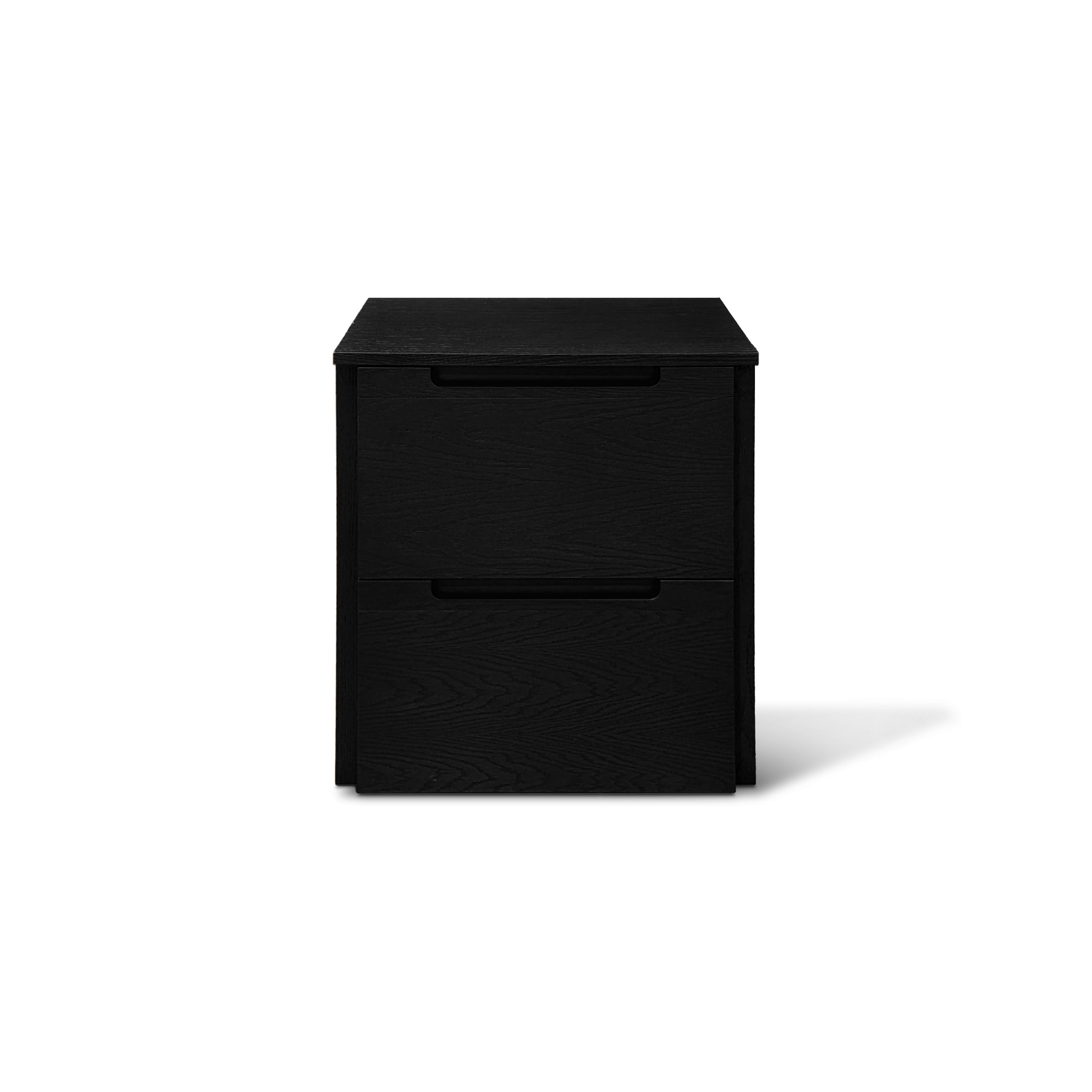 Une commode à tiroirs minimaliste Origin | ONYX de Humble Nature se dresse sur un fond blanc. Cette commode noire élégante à deux tiroirs est dotée de poignées simples, soulignant son style contemporain, avec des ombres ajoutant de la profondeur sur le côté droit.