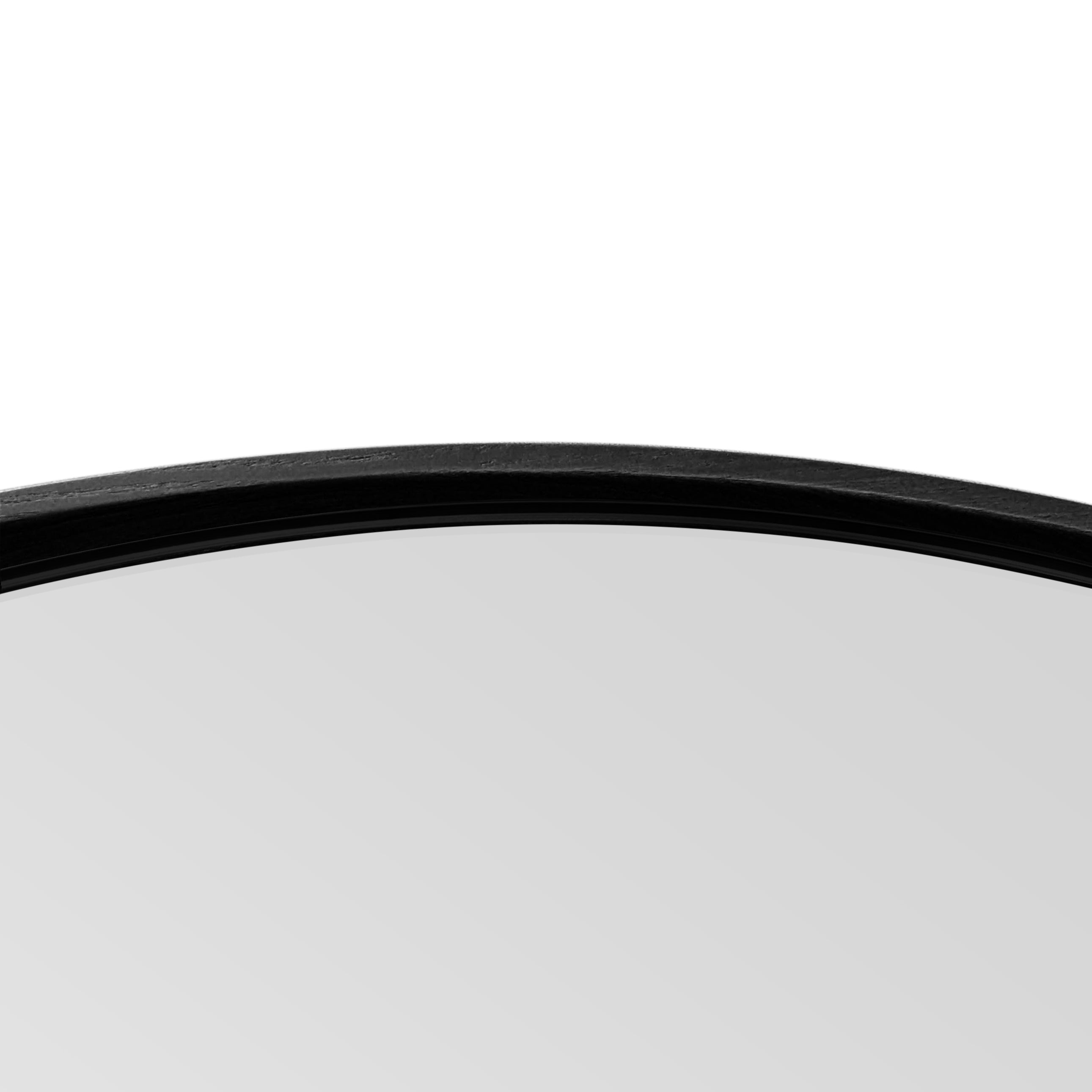 Un gros plan du Miroir 36 rond en chêne rouge Essence de Humble Nature sur fond blanc met en valeur son élégance naturelle, mettant en valeur le mélange harmonieux du verre onyx et du cadre noir.