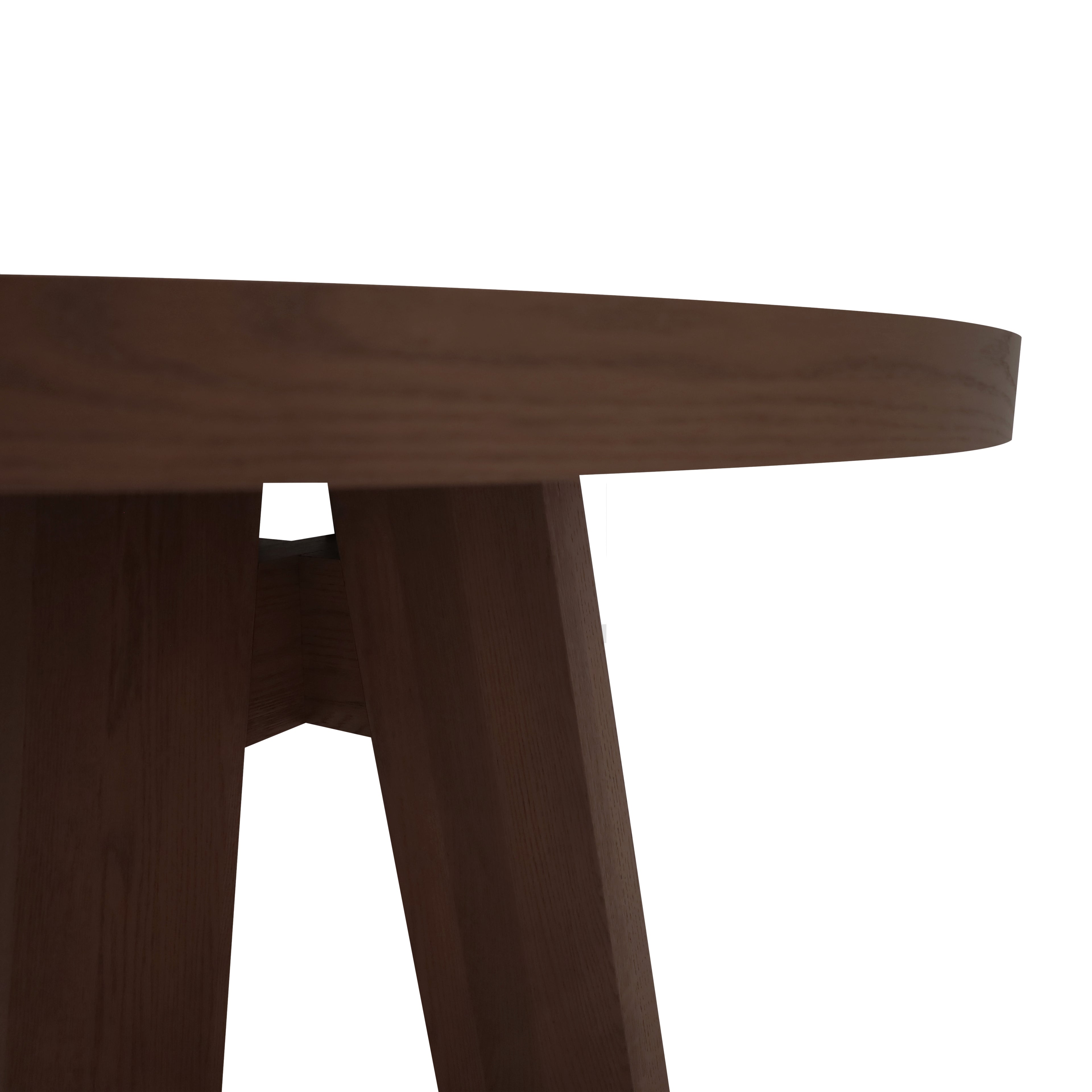 Gros plan sur le bord et les pieds en angle de la Table à dîner circulaire 48 Origin | PECAN de Humble Nature, en chêne rouge nord-américain, parfaite pour une salle à dîner et posée sur un fond blanc.