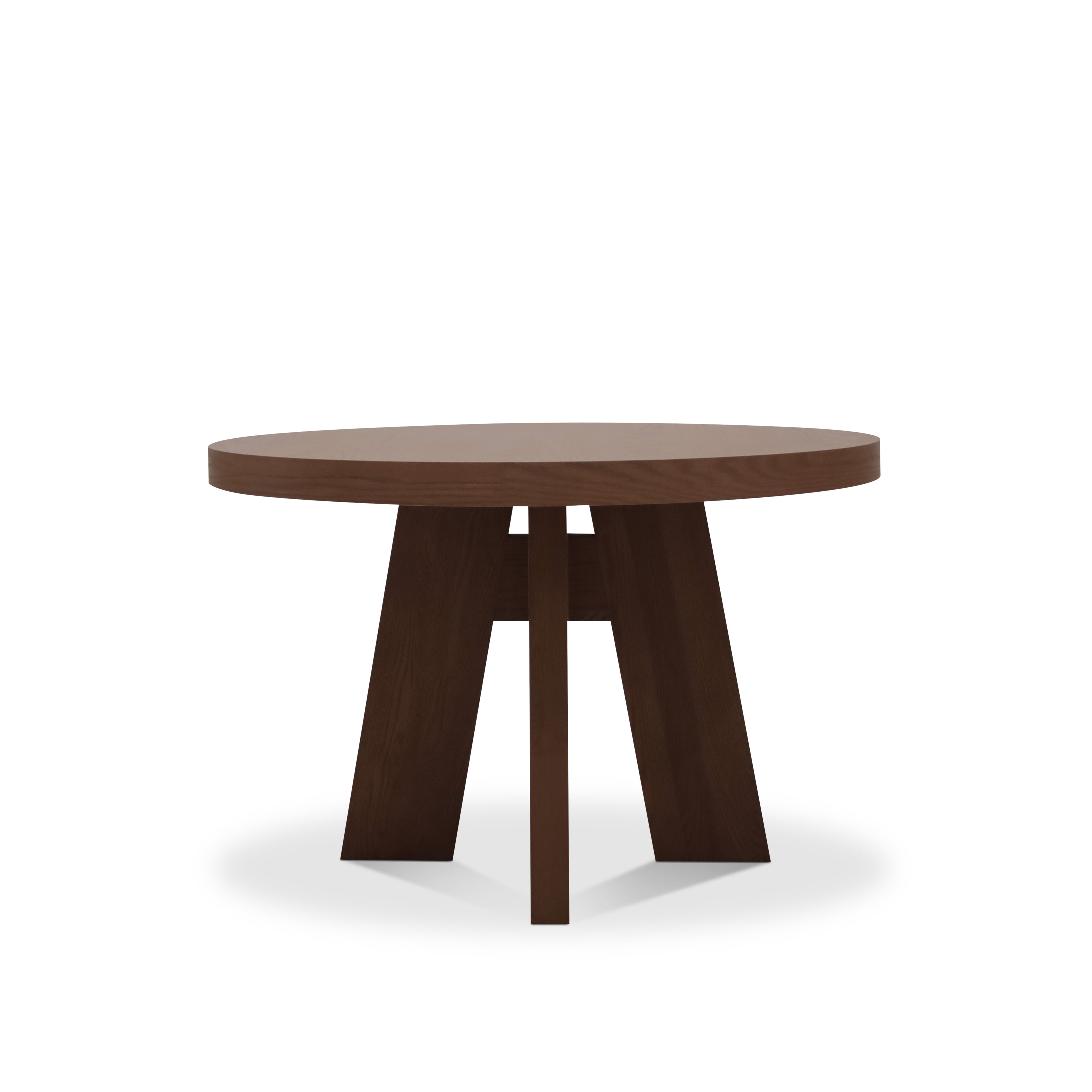 La Table à dîner circulaire 48 Origin | PECAN de Humble Nature se caractérise par un épais plateau rond en chêne rouge nord-américain marron foncé et trois larges pieds inclinés, idéaux pour rehausser votre salle à dîner, présentés sur un fond blanc uni.