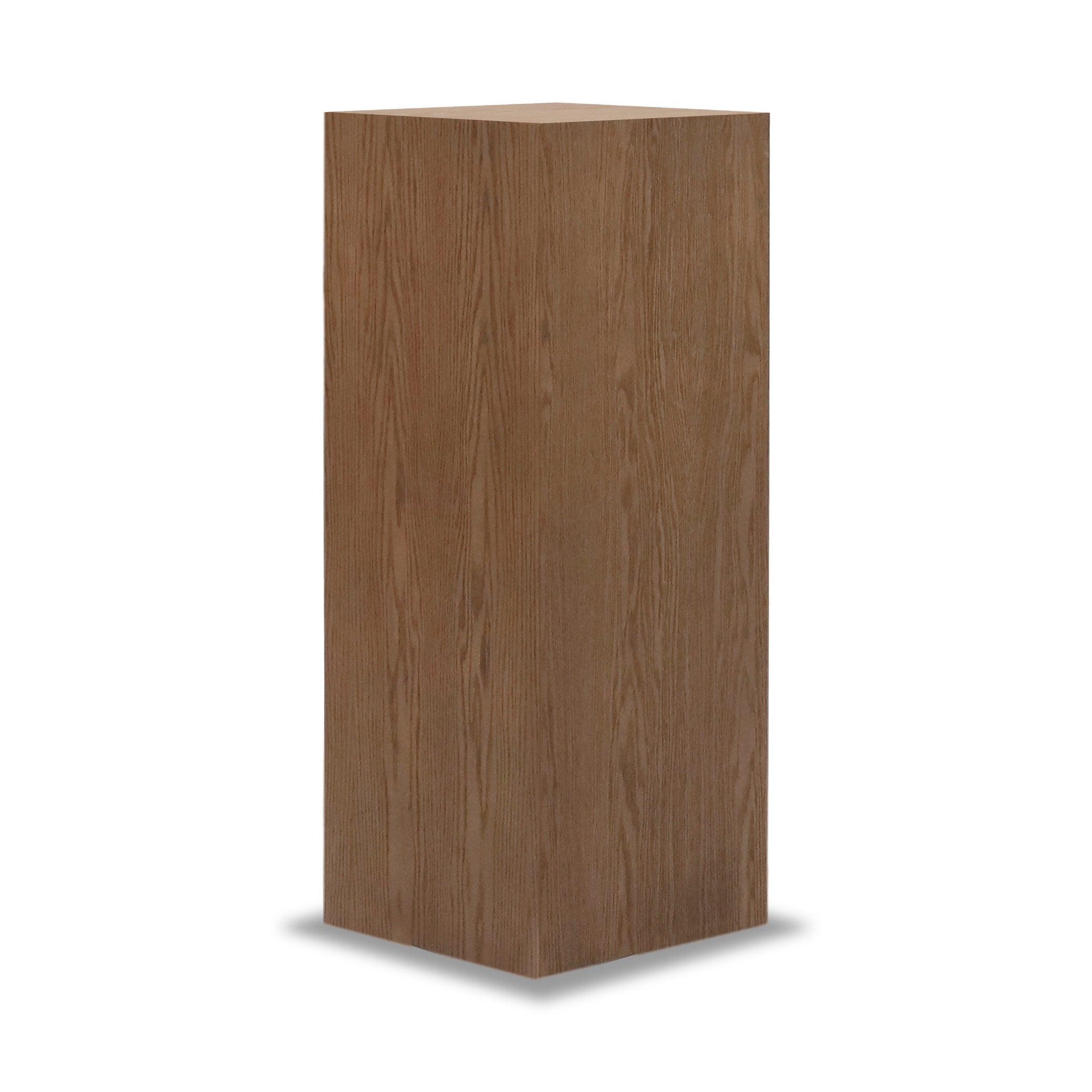 Se dressant sur un fond blanc uni se trouve la « Table piédestal carré 47 Essence | Saddle » de Humble Nature, un haut piédestal rectangulaire en bois présentant une surface lisse et un motif de grain de bois naturel qui fait écho à l&