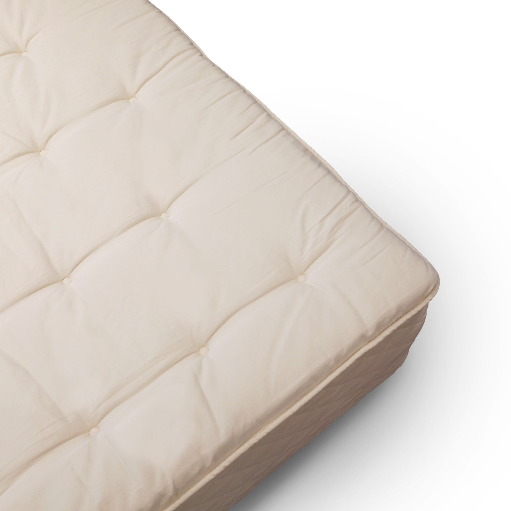 Vue dangle dun Surmatelas │ QUEEN de Obasan x Humble Nature, présentant une couleur beige avec une texture matelassée et des touffes de boutons apparentes en latex certifié biologique, offrant un aspect doux et douillet, idéal pour favoriser lamélioration du sommeil sur un fond blanc.