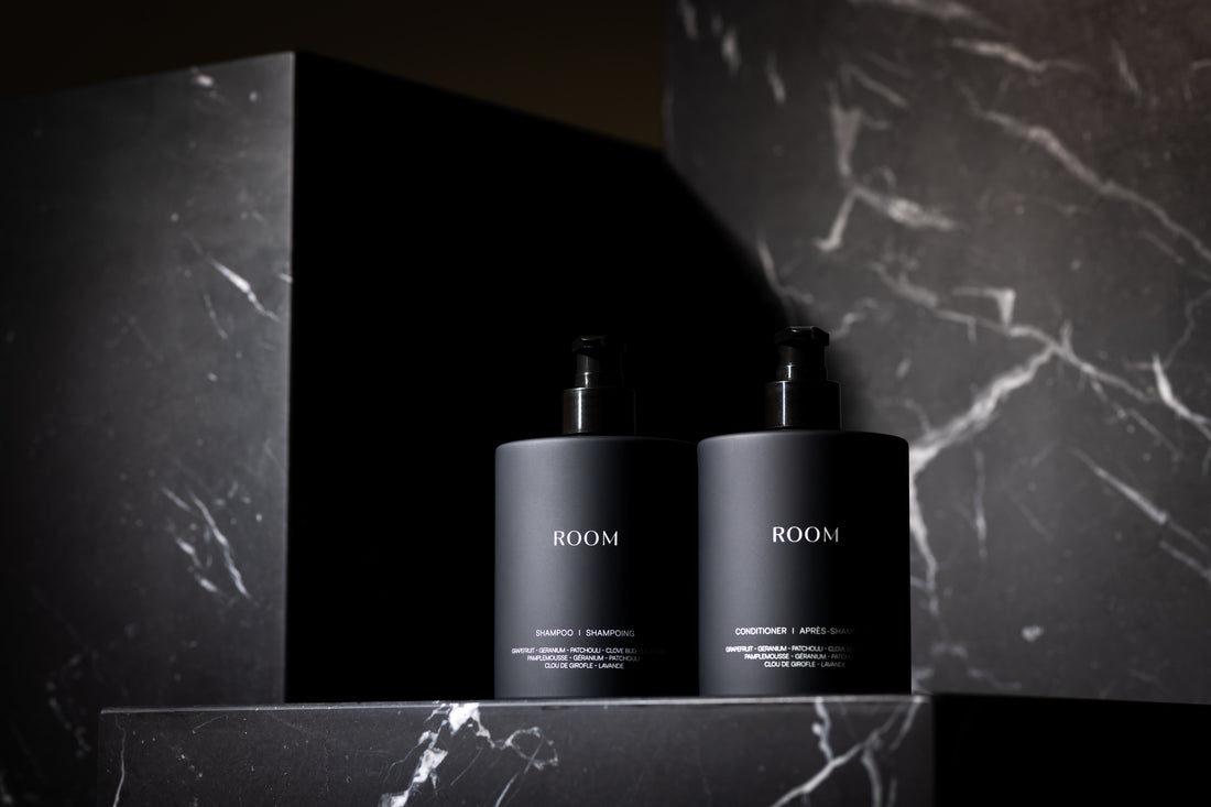 Duo de shampooing et après-shampoing ROOM en flacons noirs mats 500 ml avec pompes. Ces produits haut de gamme, enrichis en huiles essentielles naturelles, offrent une hydratation profonde et une expérience capillaire luxueuse.