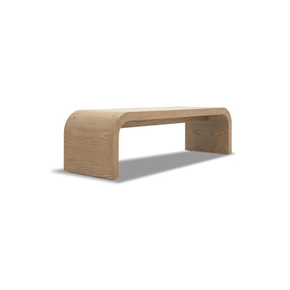 Le Banc 64 en bois Essence de Humble Nature présente un design minimaliste et incurvé en chêne rouge brun clair. Fabriqué en bois massif, sa finition lisse et son ombre douce sur fond blanc soulignent son esthétique moderne.