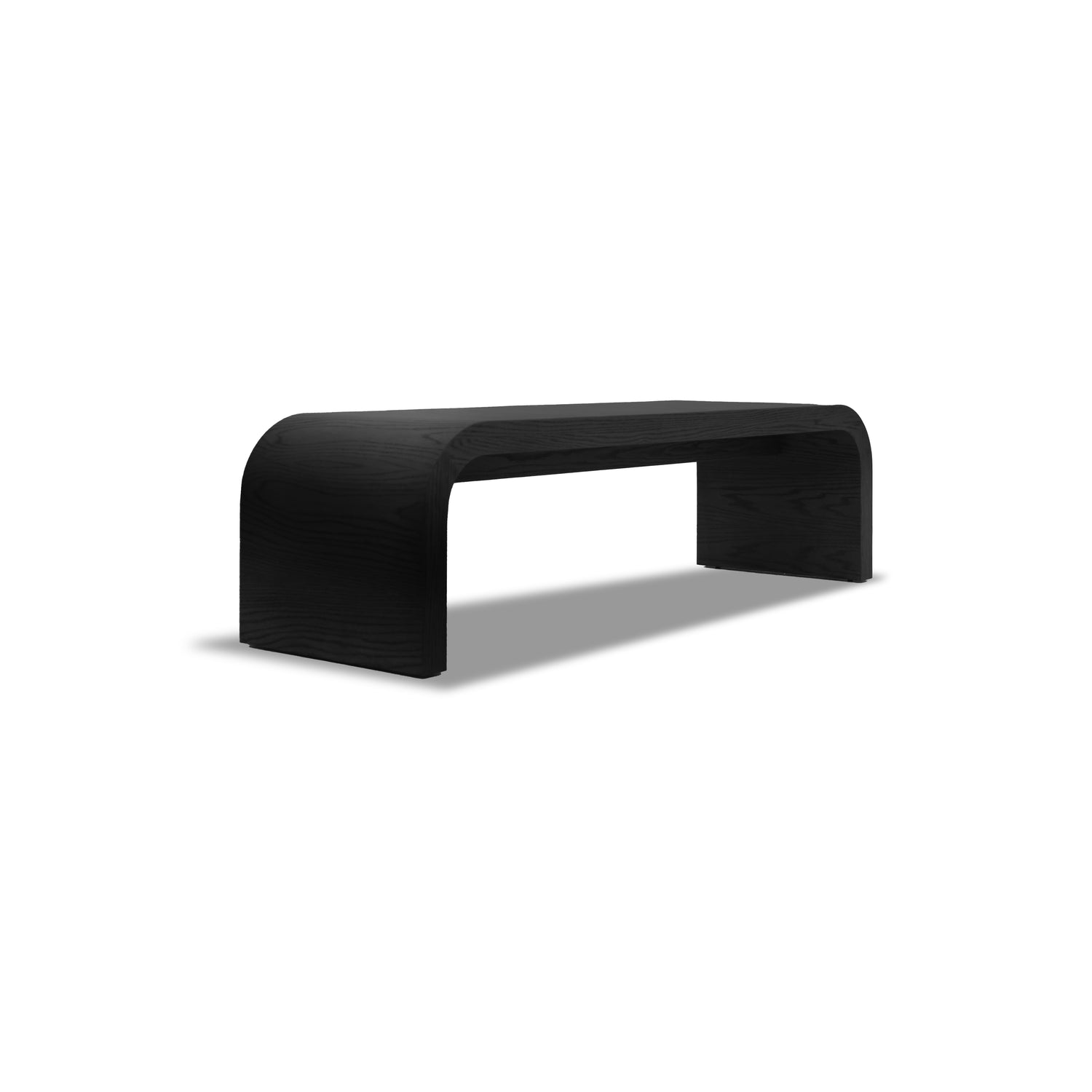 Le Banc 64 en bois Essence │ ONYX de Humble Nature est un banc minimaliste en bois noir fabriqué en bois massif. Son design incurvé et sans couture projette une ombre sur un fond blanc, soulignant son style élégant et sa sophistication simple.