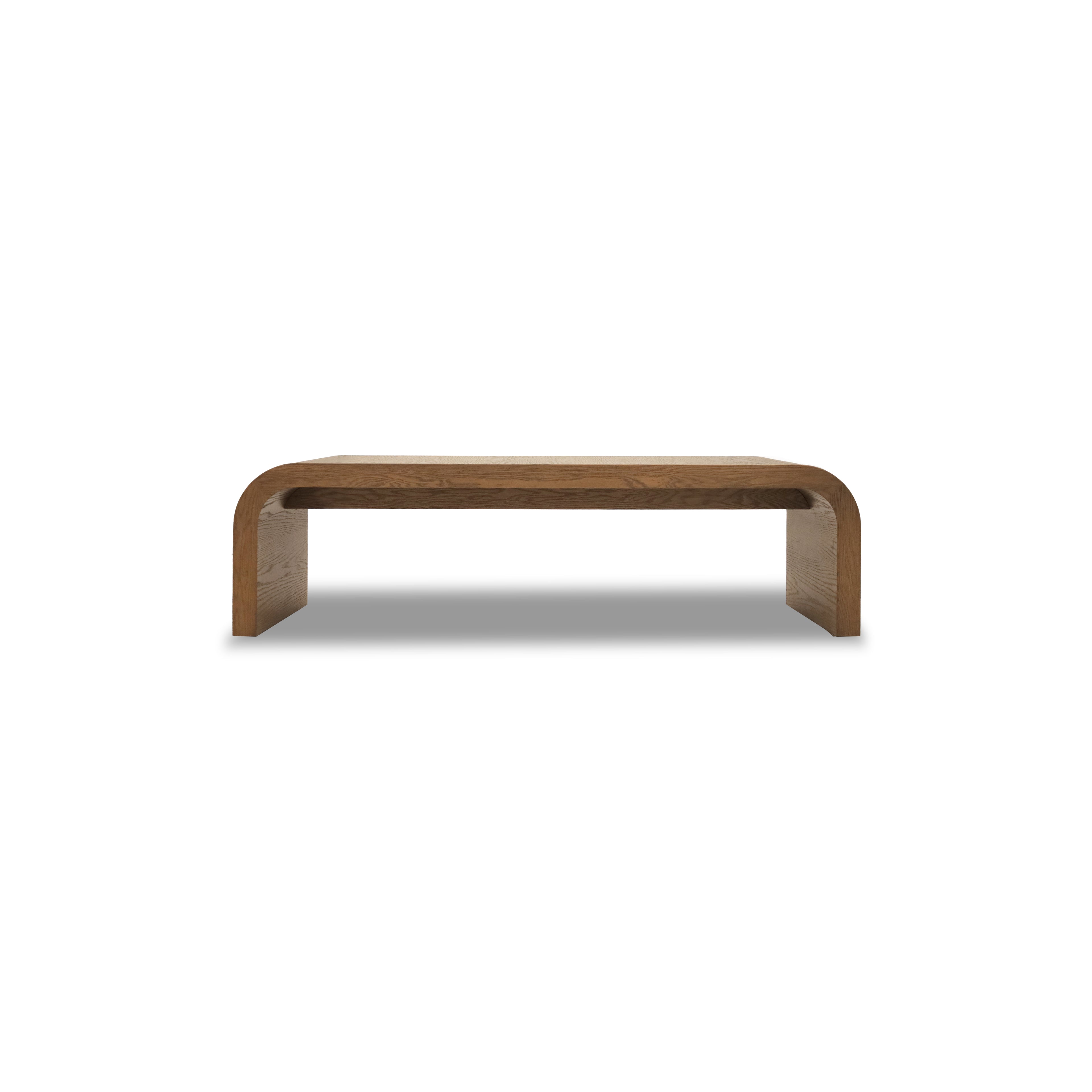 Le Banc 64 en bois Essence de Humble Nature présente un design minimaliste avec des bords incurvés et une finition lisse, sur fond blanc uni, incarnant une esthétique épurée.