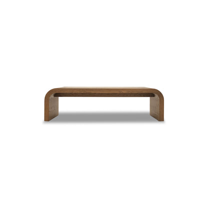 Le Banc 64 en bois Essence de Humble Nature présente un design minimaliste avec des bords incurvés et une finition lisse, sur fond blanc uni, incarnant une esthétique épurée.