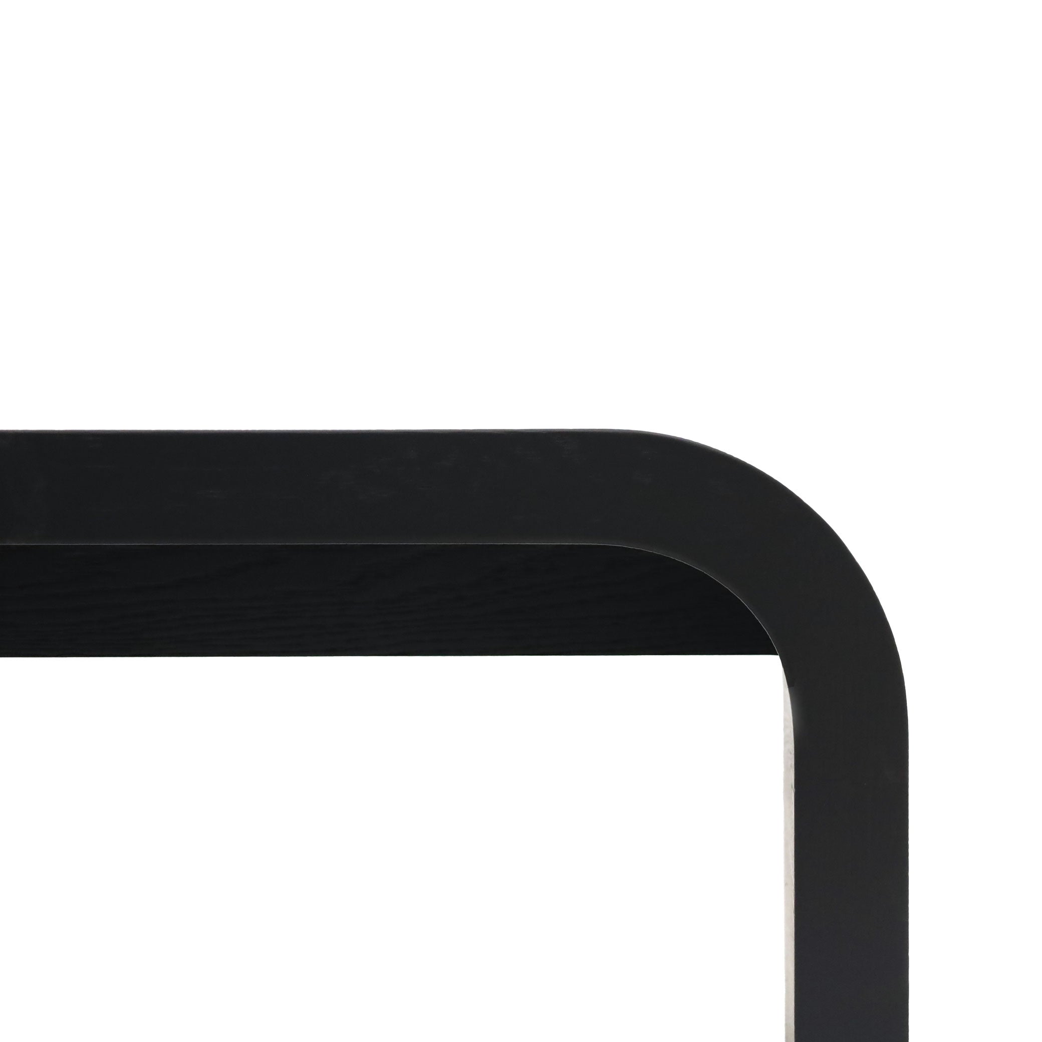 Gros plan minimaliste dun coin dun banc rectangulaire noire, mettant en valeur ses bords lisses et son design simple sur un fond blanc, rappelant lélégance raffinée du Banc 80 en bois Essence │ ONYX de Humble Nature.