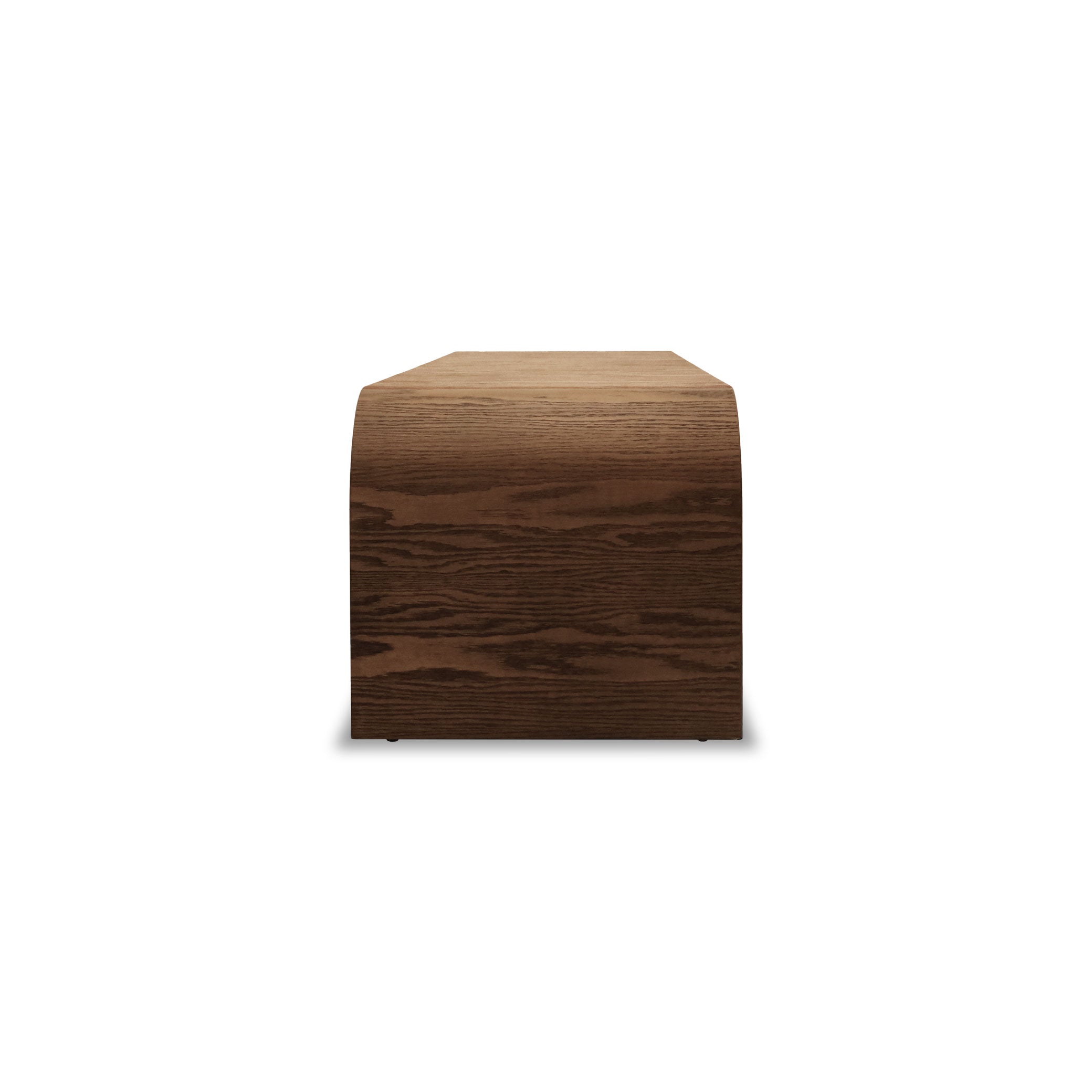 Le Banc 80 en bois Essence de Humble Nature est une table en bois minimaliste avec une surface courbée en PECAN. Sa riche teinte brune aux motifs de veinage visibles se détache élégamment sur un fond blanc.