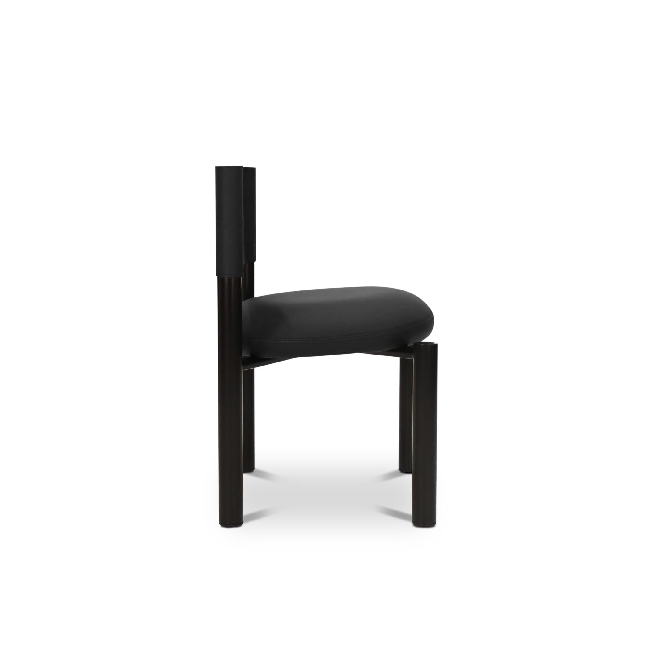 La chaise de salle à dîner en cuir Barrel | ONYX de Humble Nature présente un design moderne et minimaliste avec un siège rembourré noir, un dossier en cuir souple et une structure en métal élégant. Son design géométrique sans accoudoirs rehausse son esthétique contemporaine sur fond blanc.