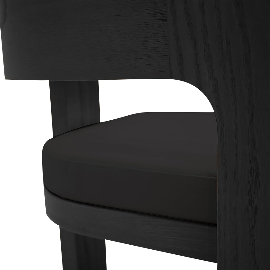 Gros plan de la Chaise de salle à dîner en bois Origin | ONYX de Humble Nature, dotée dun design moderne en bois noir avec un dossier incurvé et une assise rembourrée. Son savoir-faire exquis et ses textures mises en valeur en font un meuble idéal pour toute salle à manger.