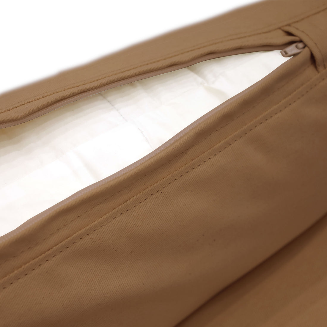 Un gros plan sur une pochette zippée beige dégage une esthétique minimaliste, avec un intérieur blanc épuré. Le design partiellement dézippé met en valeur sa texture lisse, rappelant lélégance réconfortante du canapé deux places Essence | Saddle de Humble Nature.