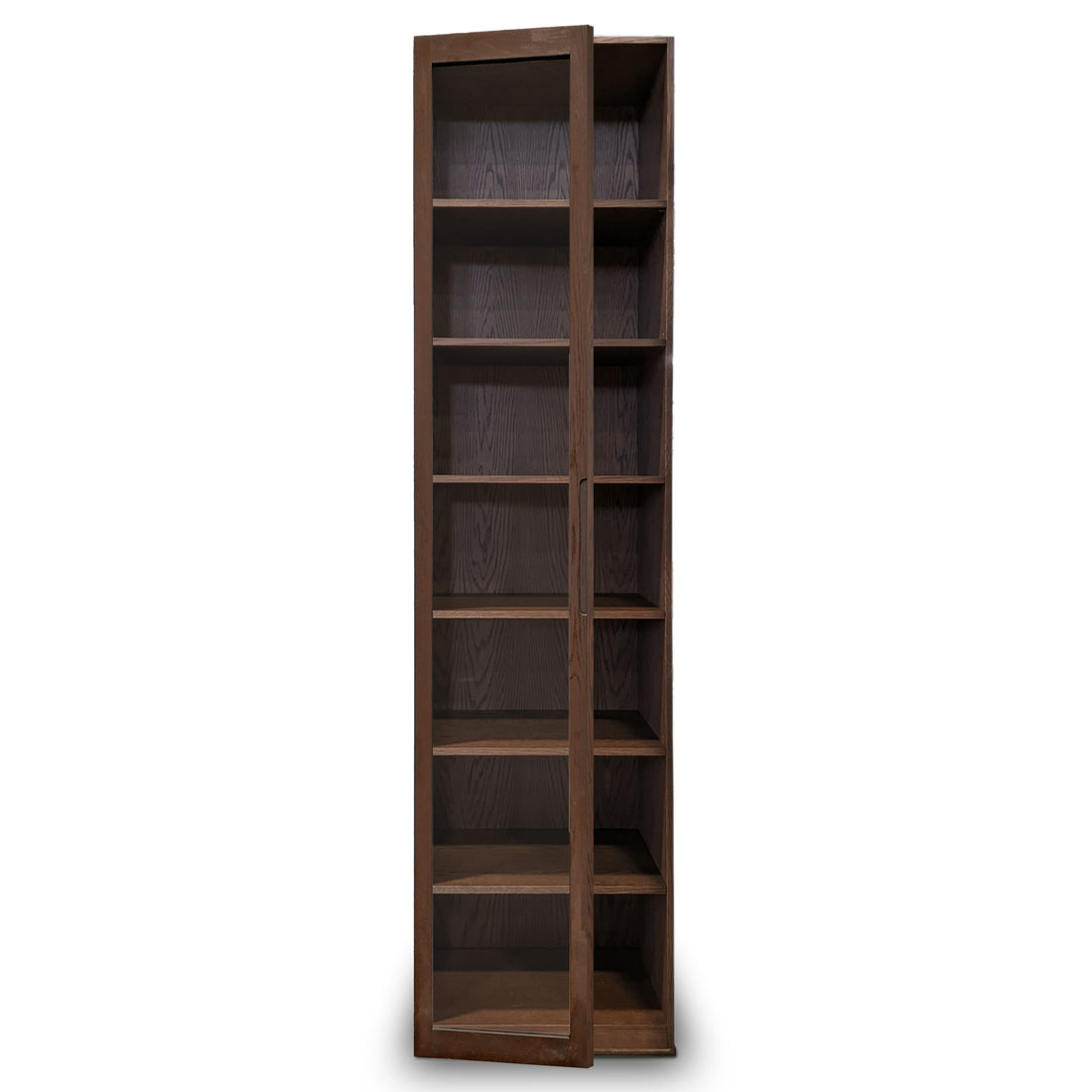 Larmoire Humble Nature simple fini pecan | porte verre est une élégante bibliothèque en bois brun foncé dotée de six étagères. Son design angulaire ressemble à un meuble de collection moderne, parfaitement adapté aux environnements haut de gamme, se détachant élégamment sur un fond blanc immaculé.