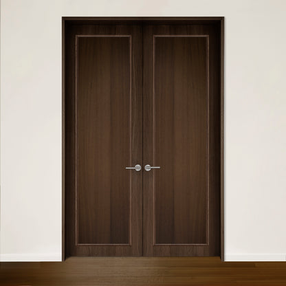 La Porte double CONTOUR en chêne rouge de Humble Nature, avec son placage en noyer brossé et ses poignées argentées épurées sur un mur blanc, respire lélégance intemporelle. Le plancher en bois complète le ton de la porte, mettant en valeur le design harmonieux.