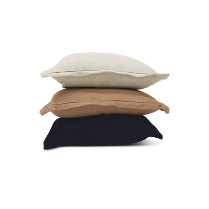 Le COUSSIN EN LIN | CLAY de Humble Nature présente trois coussins en lin superposés : beige clair, brun-brun et bleu marine foncé. Fabriqués selon des techniques de tissage traditionnelles, ces coussins unis présentent des passepoils subtils sur les bords.