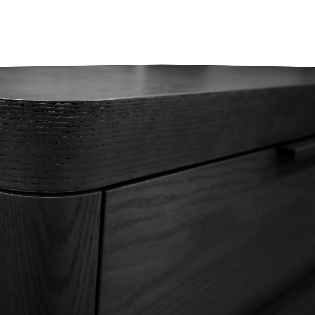 Gros plan dun coin épuré et moderne de la commode Origin | ONYX de Humble Nature, réalisée en chêne rouge avec une surface lisse et une texture subtile de grain de bois. Léclairage met en valeur son bord arrondi et son design authentique minimaliste.