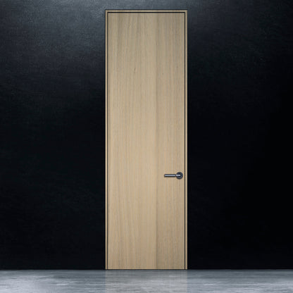 Une porte battante en bois pâle en chêne rouge placage brossé faux quartier Authentik de Humble Nature se dresse contre un mur noir. Le sol est uniformément éclairé, créant une surface réfléchissante. Le motif du grain du bois ajoute une texture subtile à son design minimaliste, alliant élégance classique et touches de modernisme.