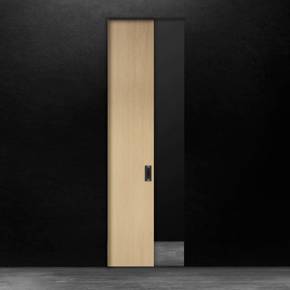 Une porte escamotable en bois pâle en chêne blanc placage brossé sur dosse de Humble Nature se dresse contre un mur noir. Le sol est uniformément éclairé, créant une surface réfléchissante. Le motif du grain du bois ajoute une texture subtile à son design minimaliste, alliant élégance classique et touches de modernisme