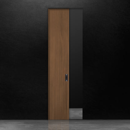 Une porte escamotable en bois brun en noyer placage de Humble Nature se dresse contre un mur noir. Le sol est uniformément éclairé, créant une surface réfléchissante. Le motif du grain du bois ajoute une texture subtile à son design minimaliste, alliant élégance classique et touches de modernisme