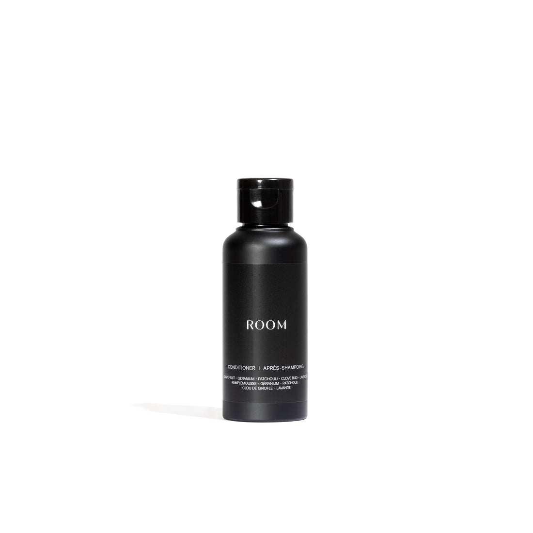 Un flacon cylindrique noir avec un bouchon noir est étiqueté « ROOM » en texte blanc et « Conditioner » en dessous. Il présente des détails de lAprès-shampoing régénérant entièrement naturel de Leroy Williams x Humble Nature et est infusé dhuile essentielle pour cheveux bien nourris, sur un fond blanc.