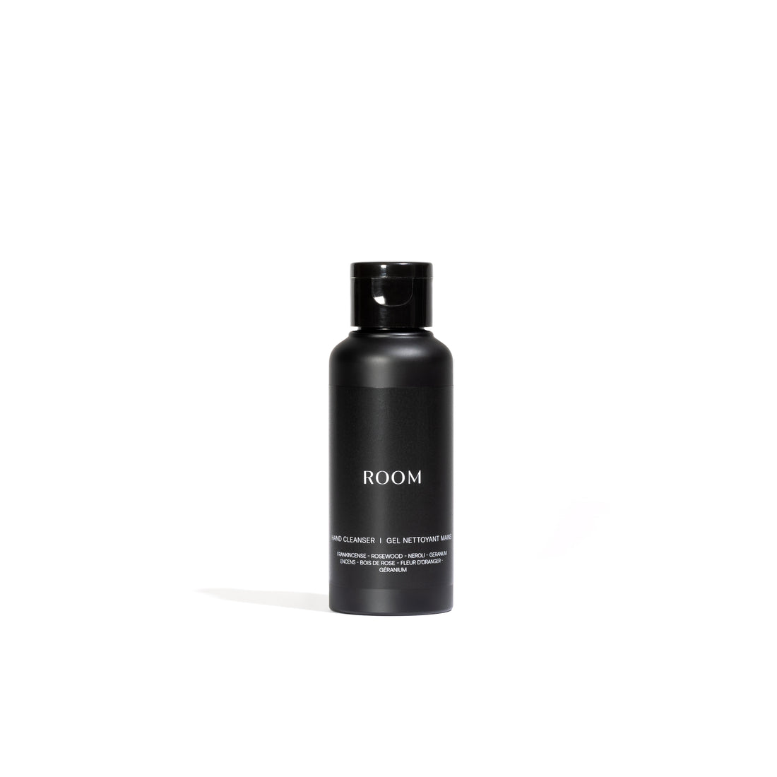 Le « Gel nettoyant botanique pour les mains entièrement naturel │ ÉCHANTILLON » de Leroy Williams x Humble Nature présente un flacon cylindrique noir minimaliste avec un bouchon noir, infusé dhuiles essentielles. Le mot « ROOM » est imprimé en blanc, renforçant son attrait naturel sur un fond blanc.