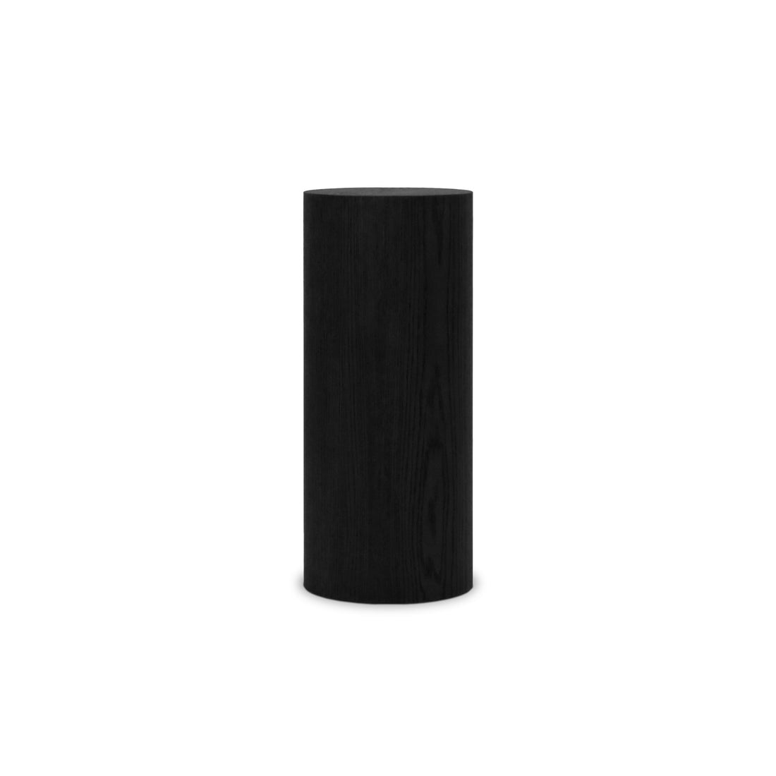 Une grande forme cylindrique noire - la table piédestal circulaire 28 Essence en Onyx de Humble Nature - se dresse debout sur un fond blanc, sa surface lisse et épurée reflétant lélégance souvent associée aux tables dappoint.