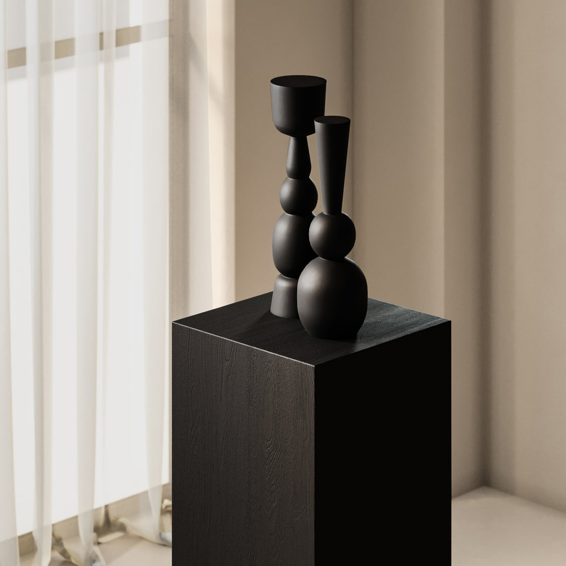 Deux tables piédestal carrées Essence | Onyx de Humble Nature, ornées de vases noirs géométriques modernes, trônent dans une pièce minimaliste avec tables basses. La lumière traverse des rideaux blancs transparents, projetant des ombres douces et créant une atmosphère élégante et sereine.