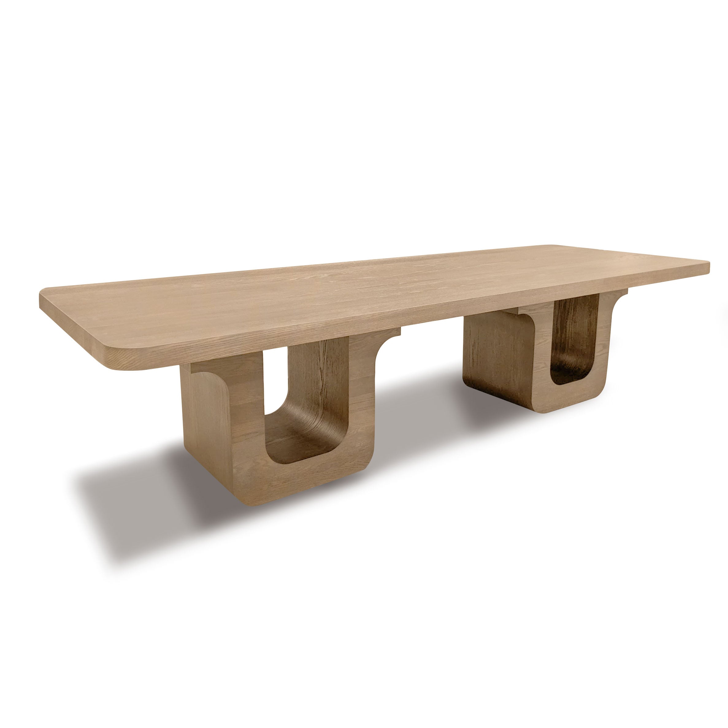 La Table à dîner 120 Suite │ PECAN de Humble Nature est une superbe pièce maîtresse. Cette longue table rectangulaire en bois présente une surface lisse et deux pieds en U, avec une riche finition naturelle rappelant le placage de chêne rouge, projetant une ombre subtile sur le fond blanc.