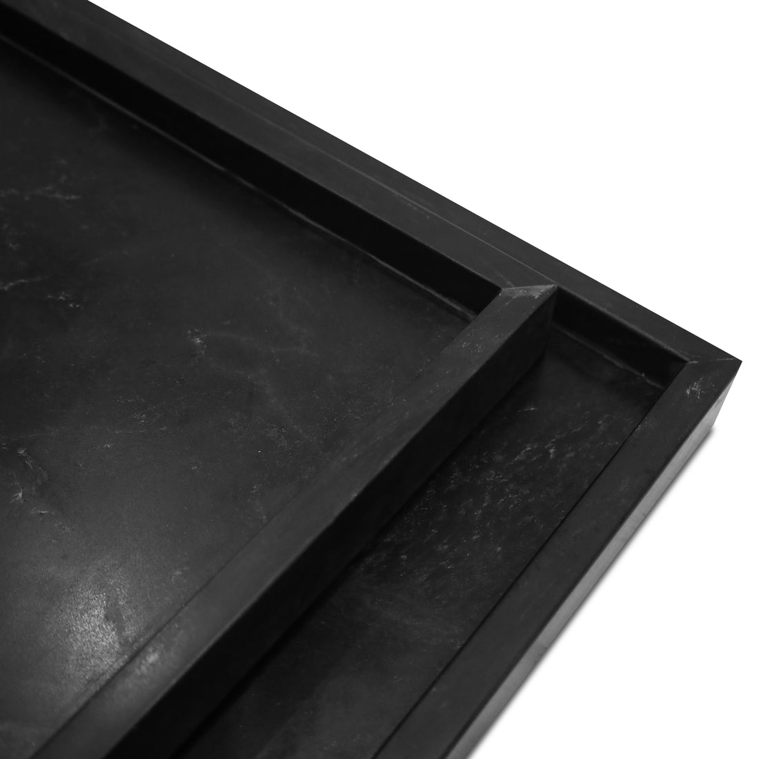 Un gros plan de lENSEMBLE DE PLATEAUX DE PIERRE NATURELLE | ONYX de Humble Nature révèle un plateau carré noir mat aux textures semblables à du marbre. Limage met en valeur son design minimaliste élégant et chaleureux, avec deux bords à angle droit.