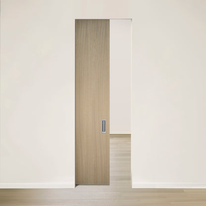 Un intérieur moderne est doté de la Porte Pure escamotable en chêne rouge placage brossé sur dosse Authentik de Humble Nature, une porte coulissante en bois clair partiellement ouverte placée dans un mur blanc cassé. Les lignes épurées et la palette neutre créent une atmosphère calme et contemporaine avec un plancher en bois clair.