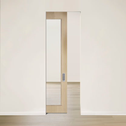 Lintérieur minimaliste est doté de la « Porte See escamotable en chêne blanc placage brossé sur dosse » de Humble Nature, une porte coulissante en bois clair avec un panneau de verre favorisant la lumière naturelle. Elle est partiellement ouverte pour révéler une pièce avec un parquet en bois clair assorti.